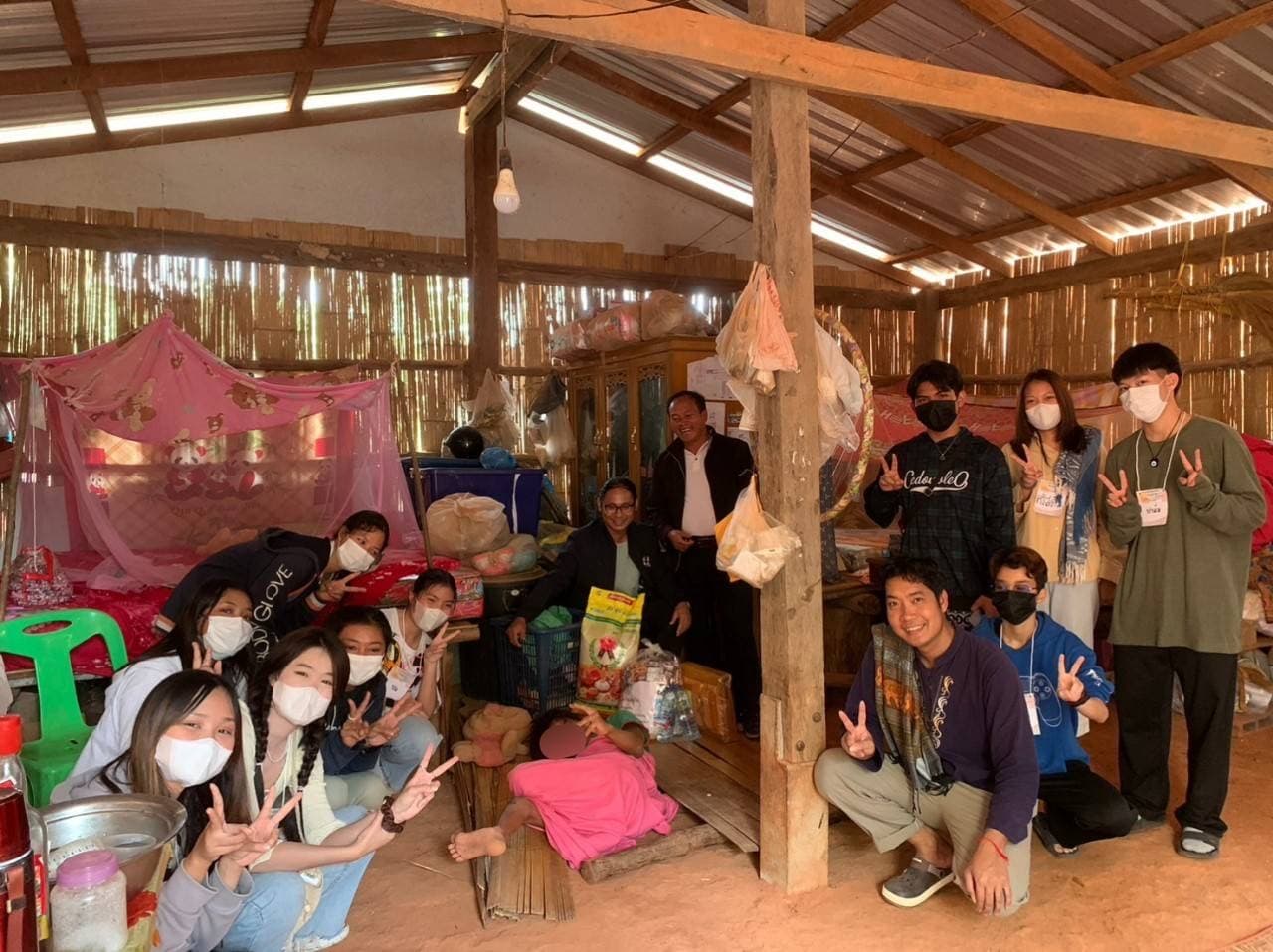 Volunteers inside a bamboo home with sacks of rice and packs of drinking water