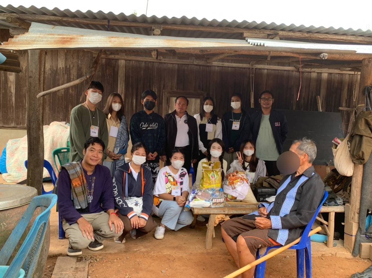 Volunteers visiting a wooden house with rice and household supplies for a local family