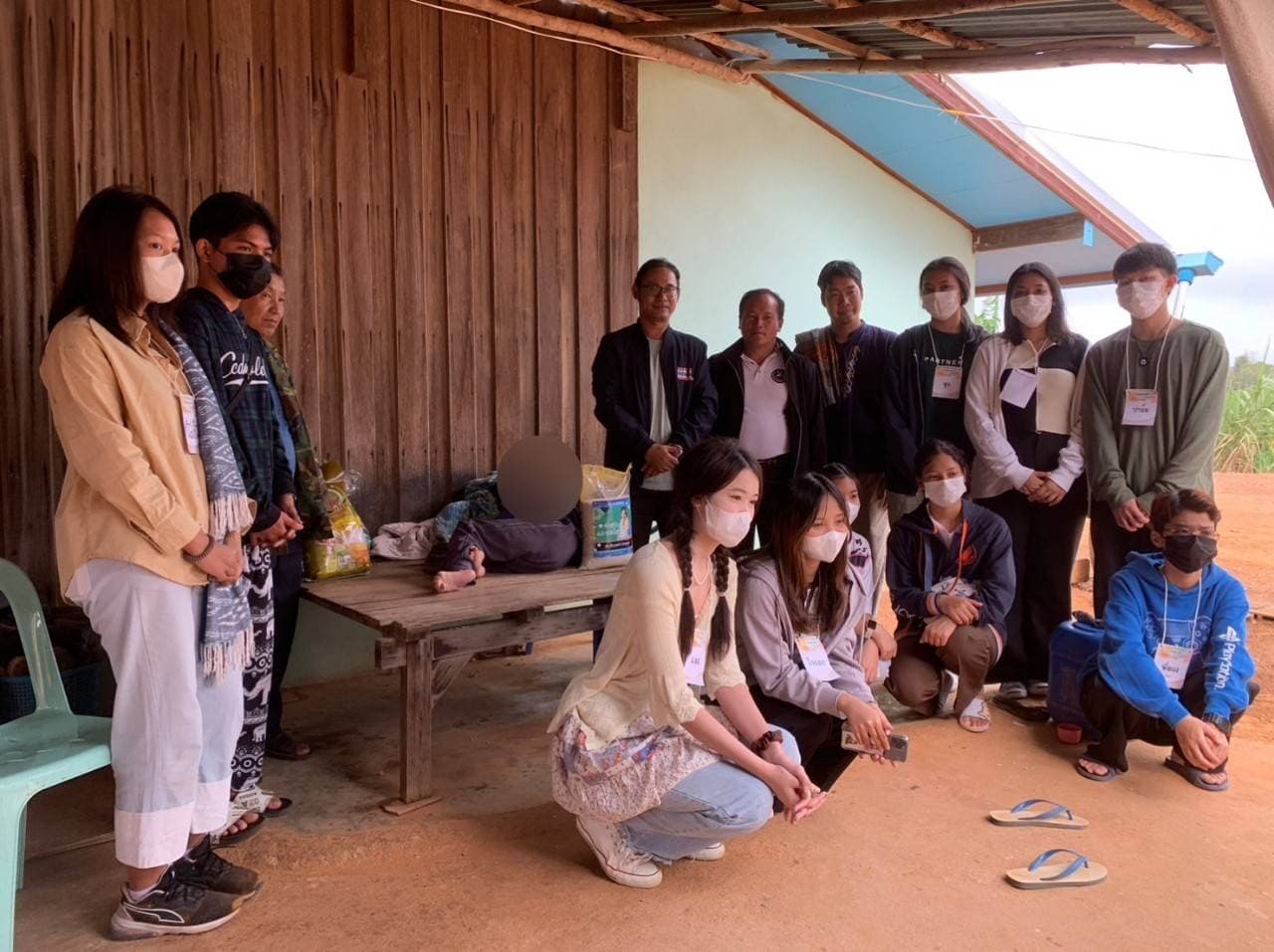 The volunteer team gathered in front of a wooden highland house after a family visit